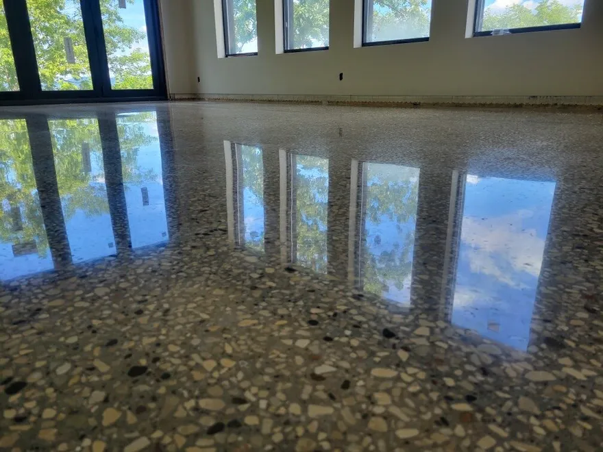 Glossy polished concrete floor with exposed aggregate reflecting large windows