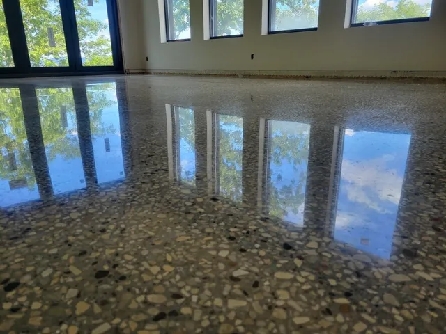 Glossy polished concrete floor with exposed aggregate reflecting large windows